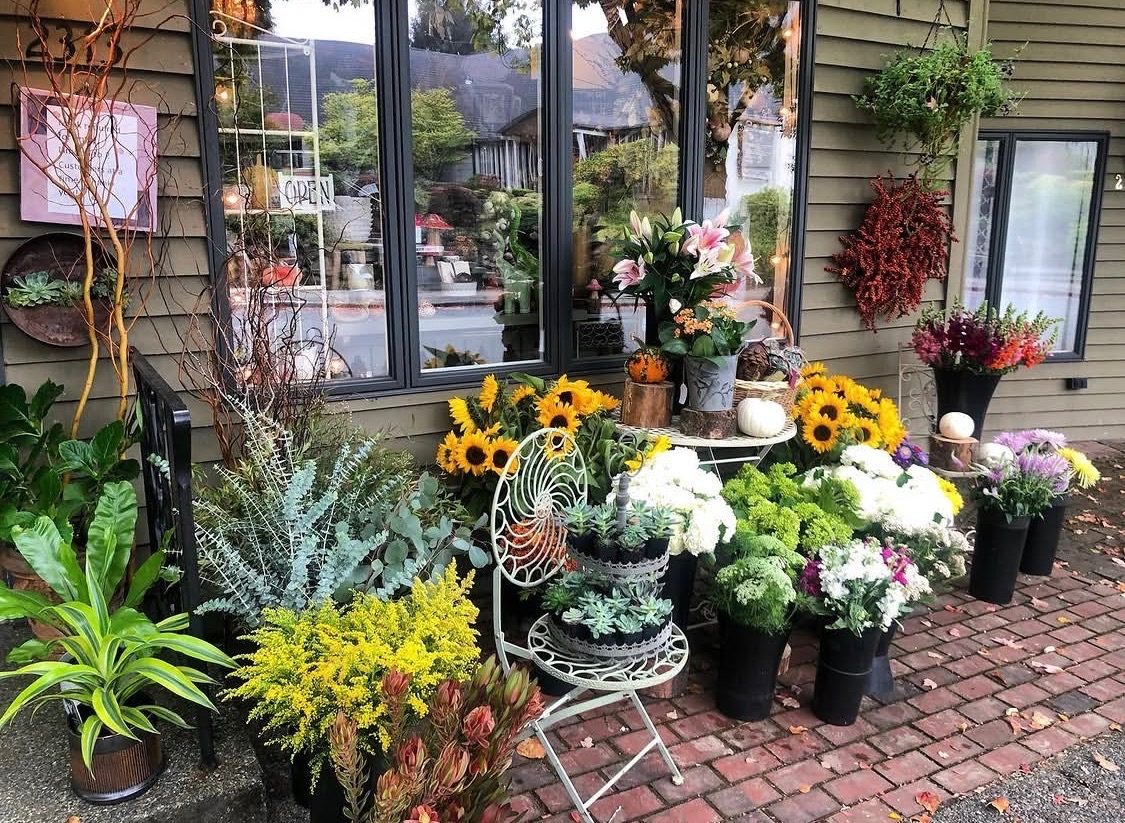 Flower shop entrance with sidewalk display of seasonal blooms, plants and cut stems